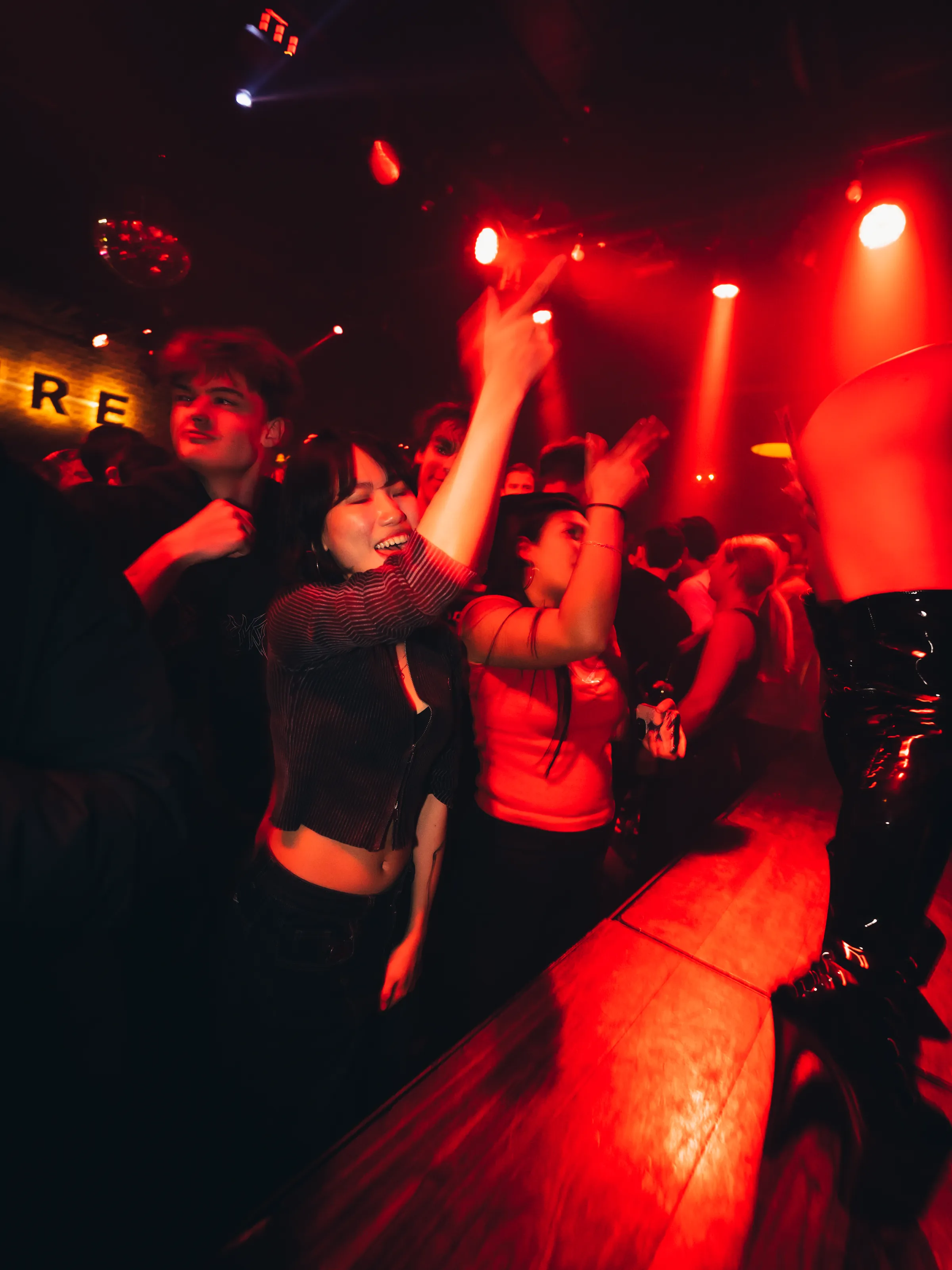 赤い照明に染まったPUREのフロアで、手を上げて踊るゲストたち